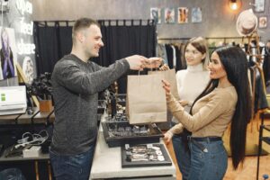 Buyer Trust and Perceived Authority in Marketing Shopkeeper handing bag to happy customer.