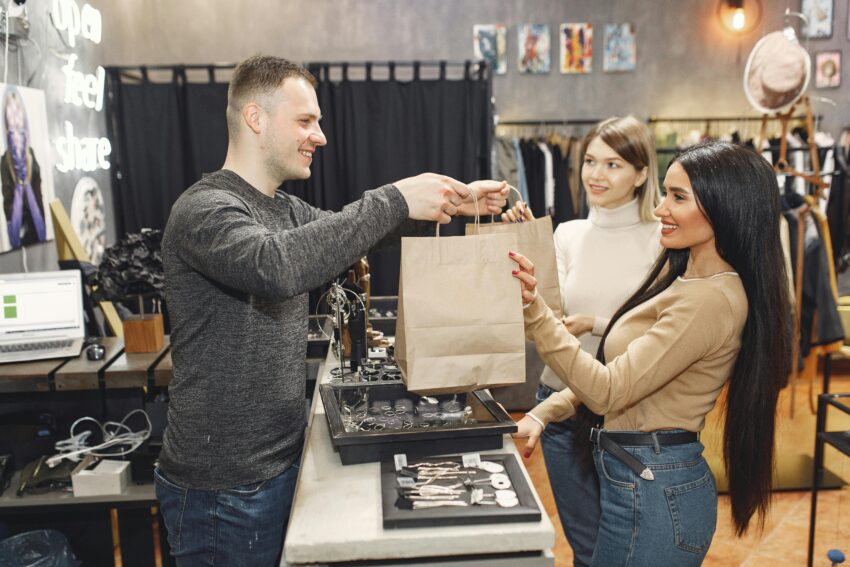 Buyer Trust and Perceived Authority in Marketing Shopkeeper handing bag to happy customer.